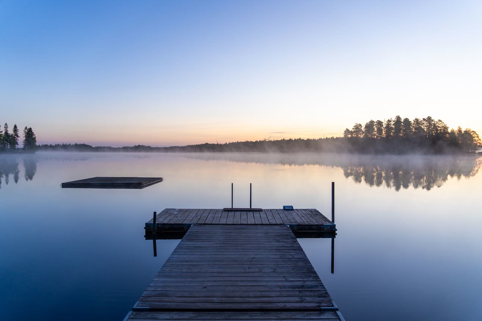 Dock reflected in a calm misty lake
